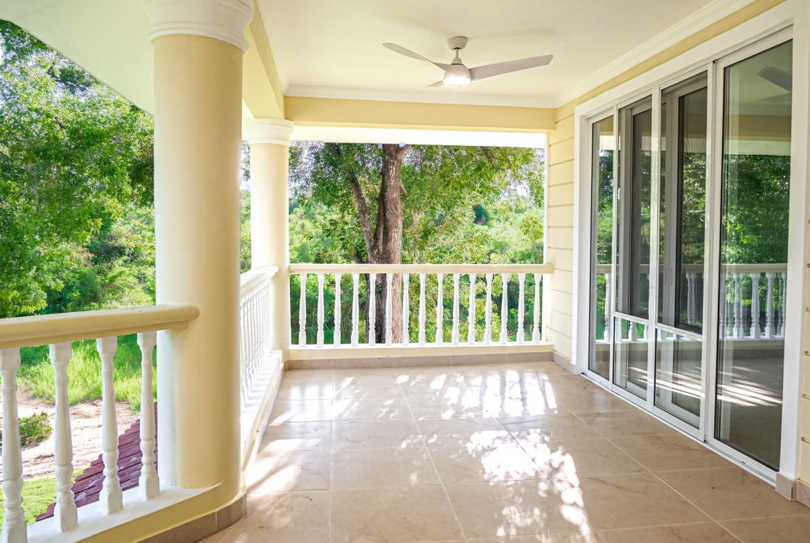 Spacious covered balcony with sliding glass doors and tropical garden views at Hispaniola Beach condo in Sosua