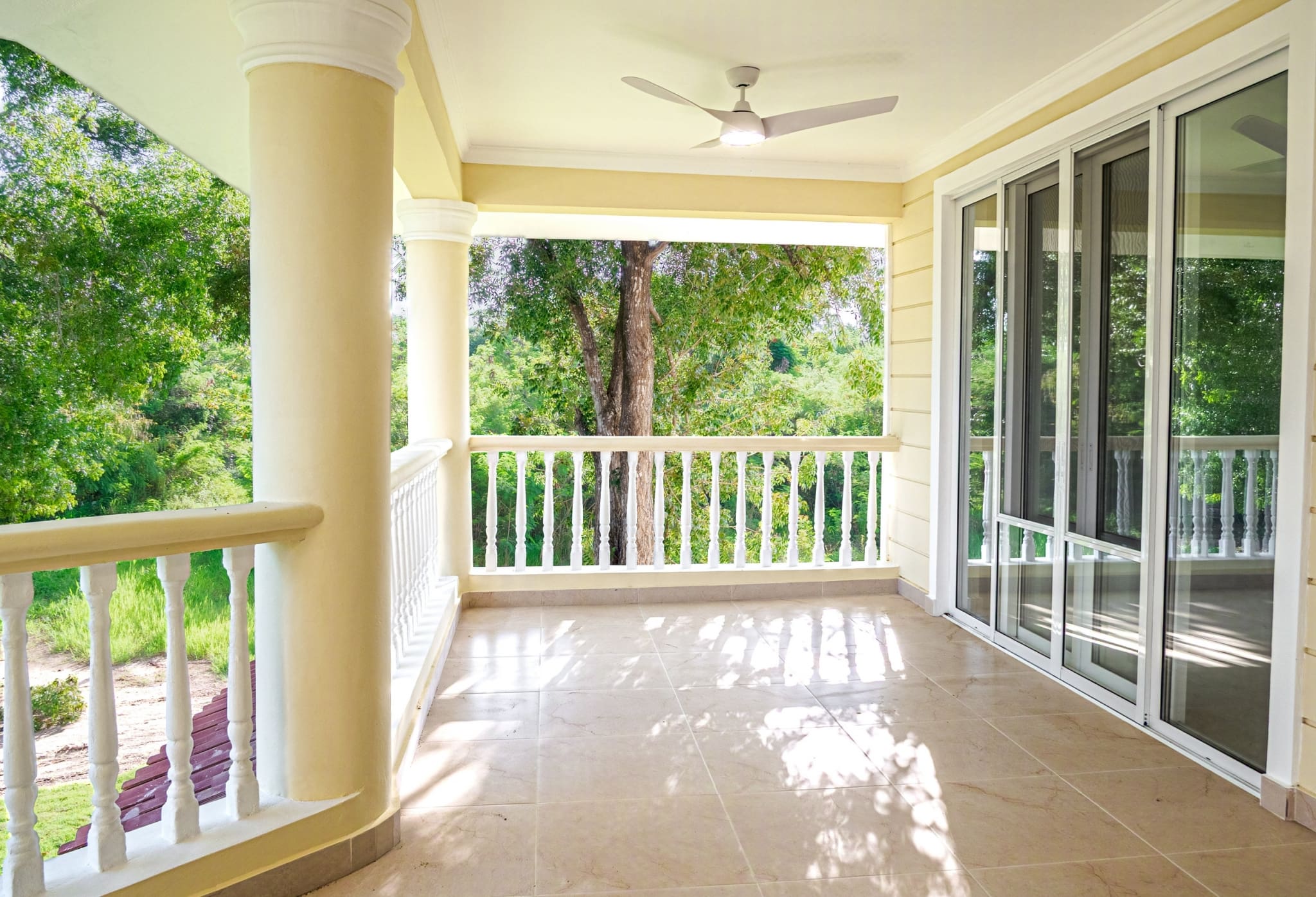 Spacious covered balcony with sliding glass doors and tropical garden views at Hispaniola Beach condo in Sosua