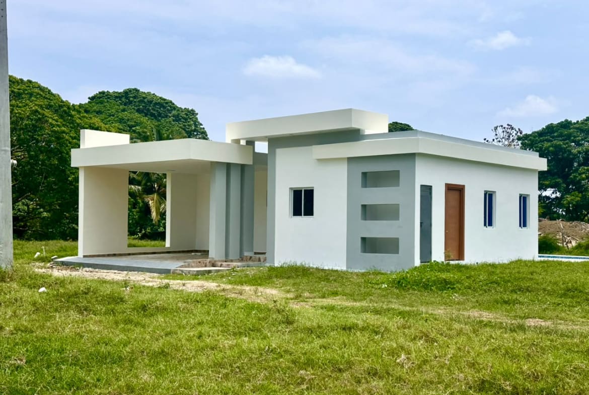 Modern white and gray house with a covered porch and green lawn Sosua Real Estate