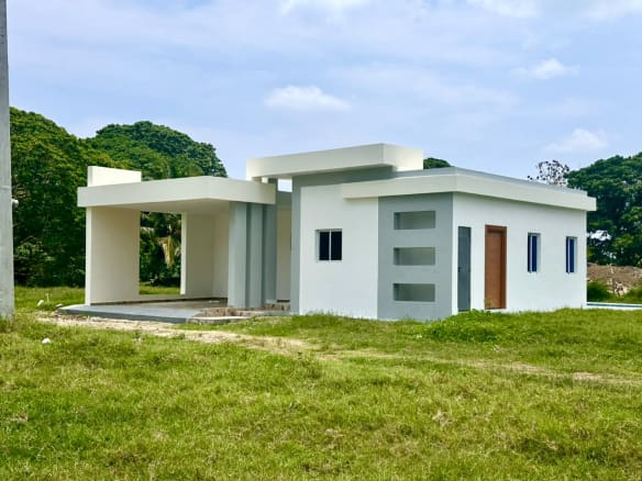 Modern white and gray house with a covered porch and green lawn Sosua Real Estate