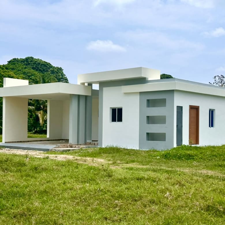 Modern white and gray house with a covered porch and green lawn Sosua Real Estate