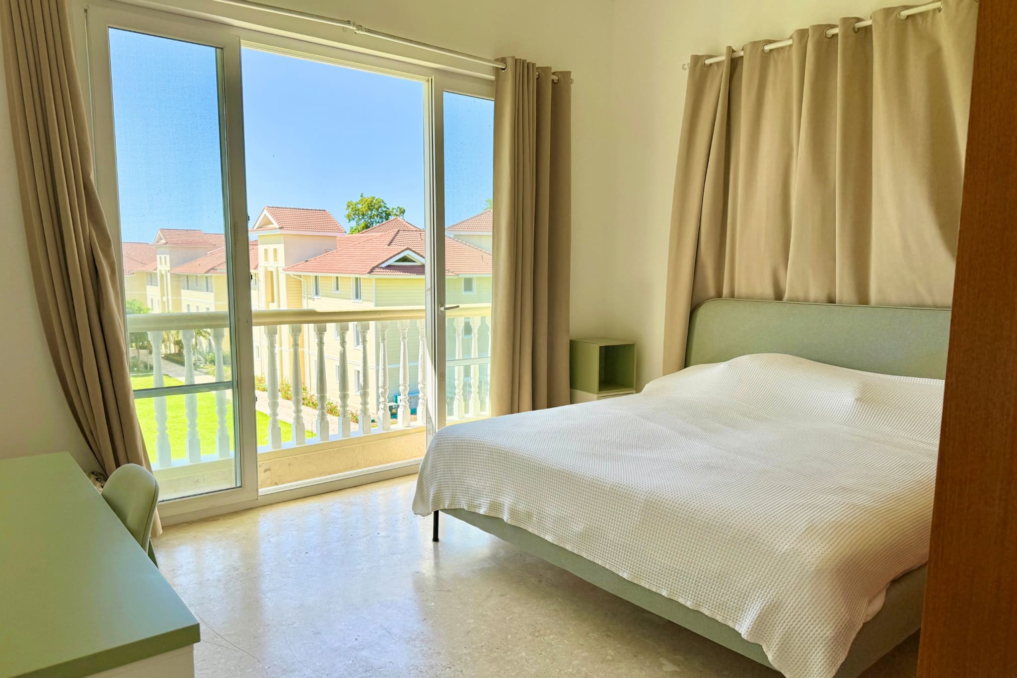 Bedroom with a large window overlooking a residential complex and a balcony