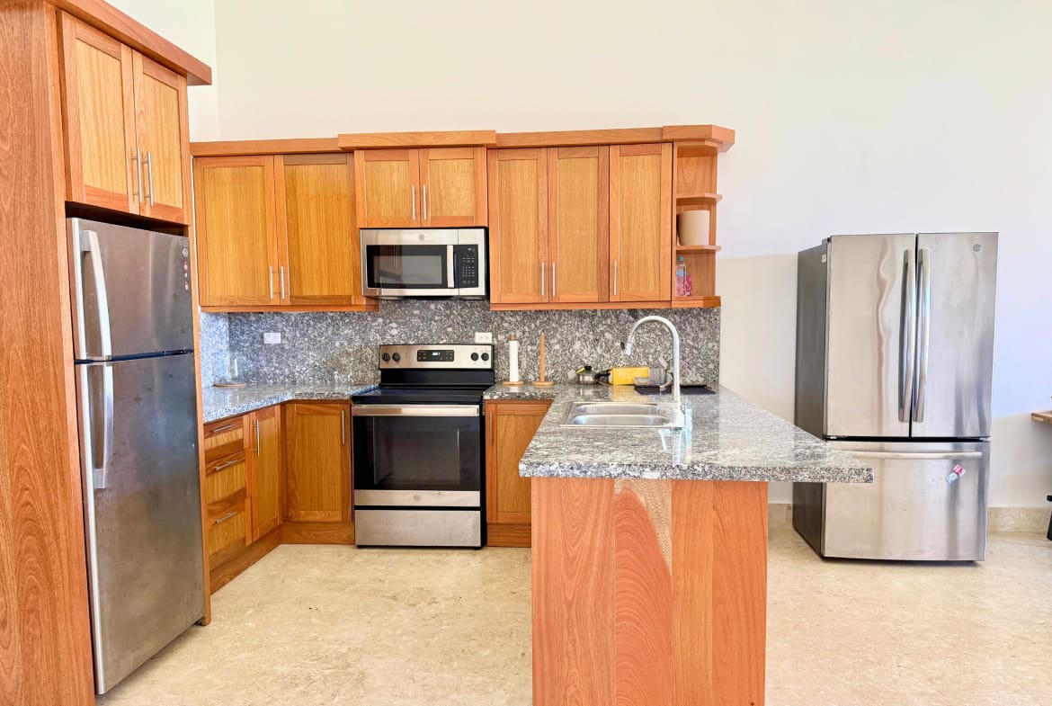 Modern kitchen with stainless steel appliances, granite countertops, and wood cabinets.