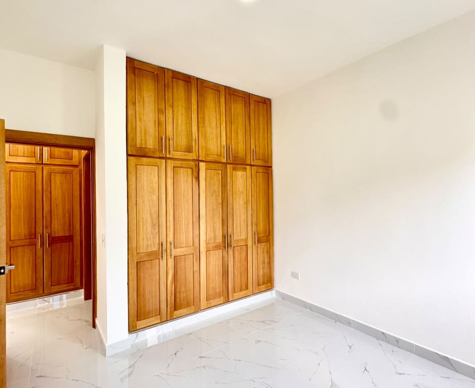 Modern bedroom with large wooden built-in wardrobes and white marble flooring Sosua Real Estate
