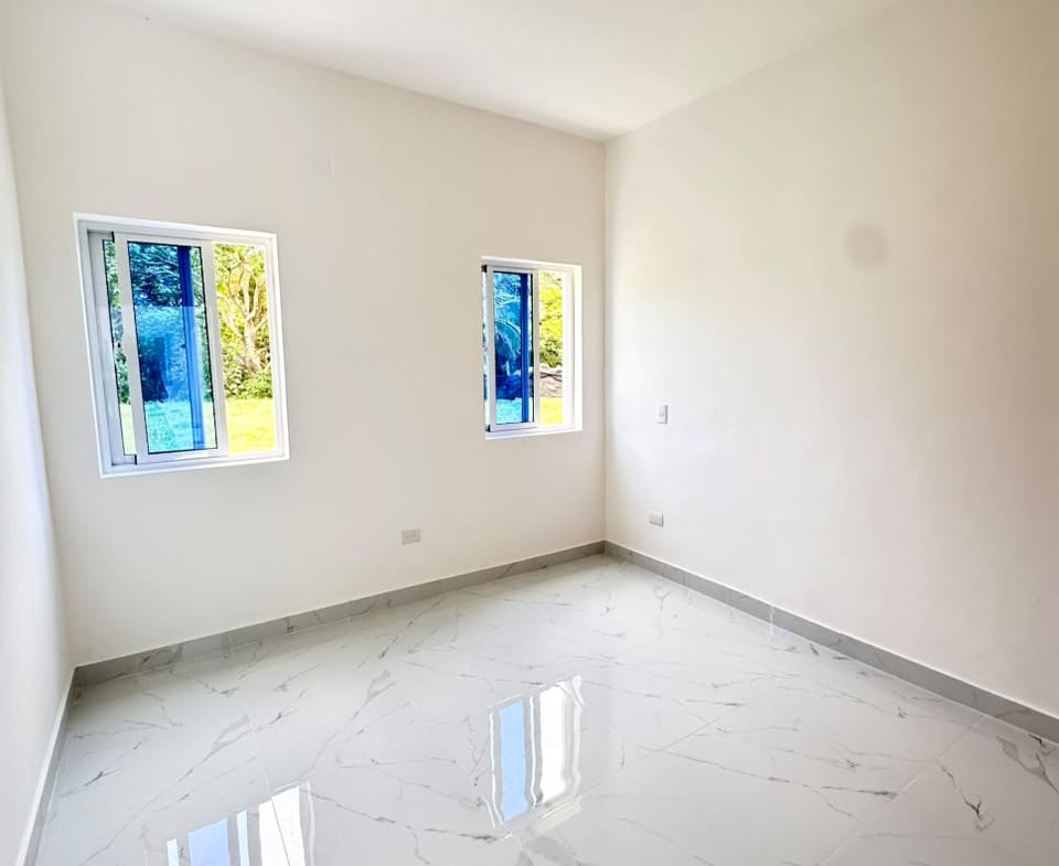Empty room with white walls, marble tile floors, and blue-tinted windows