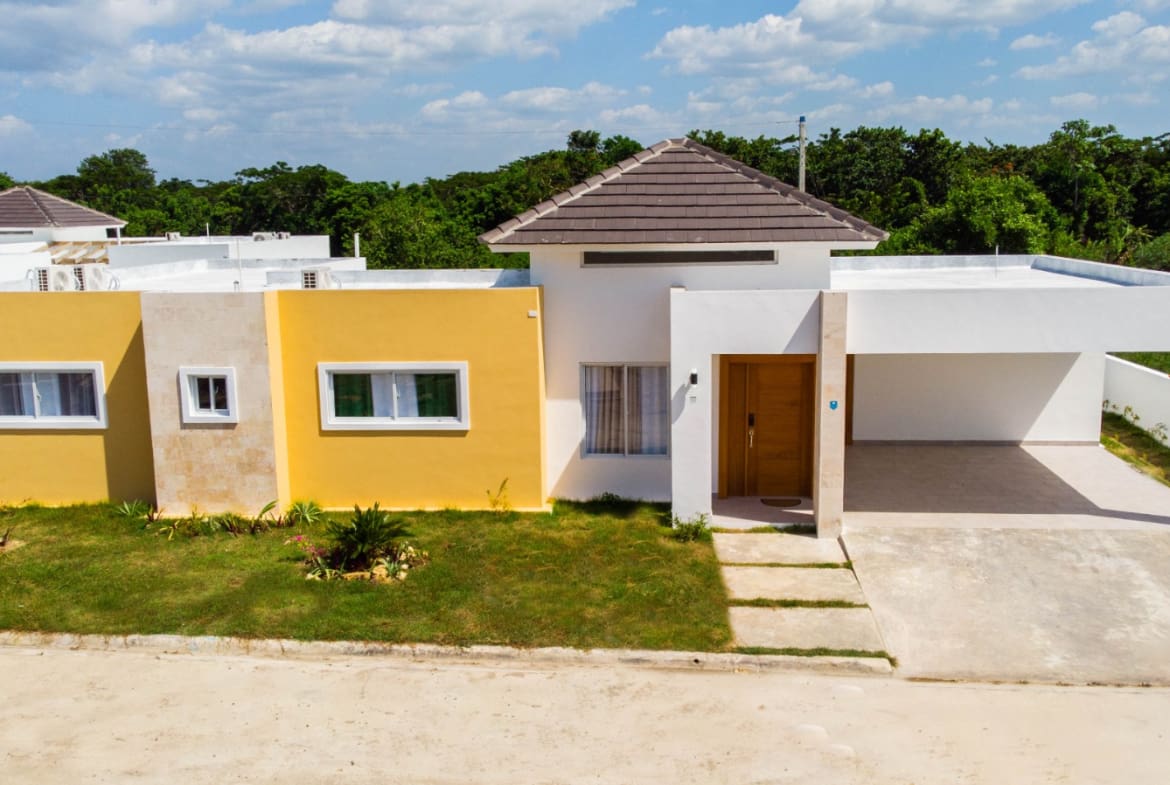 Modern yellow and white house with carport and green lawn
