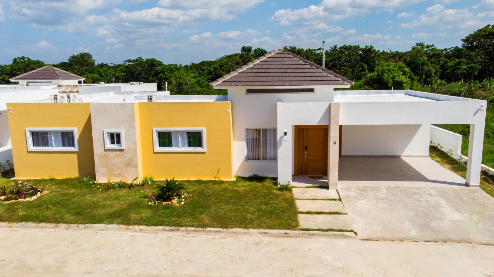 Modern yellow and white house with carport and green lawn