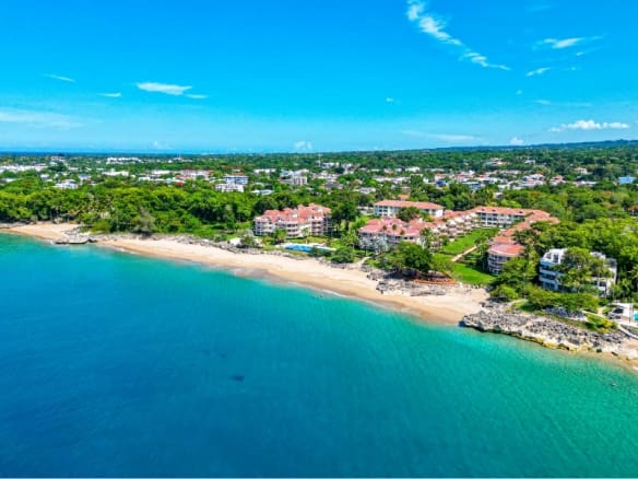 Aerial view of a tropical beachfront resort with turquoise waters and lush greenery.