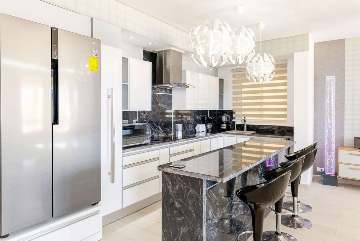Modern white kitchen with black marble island and bar stools