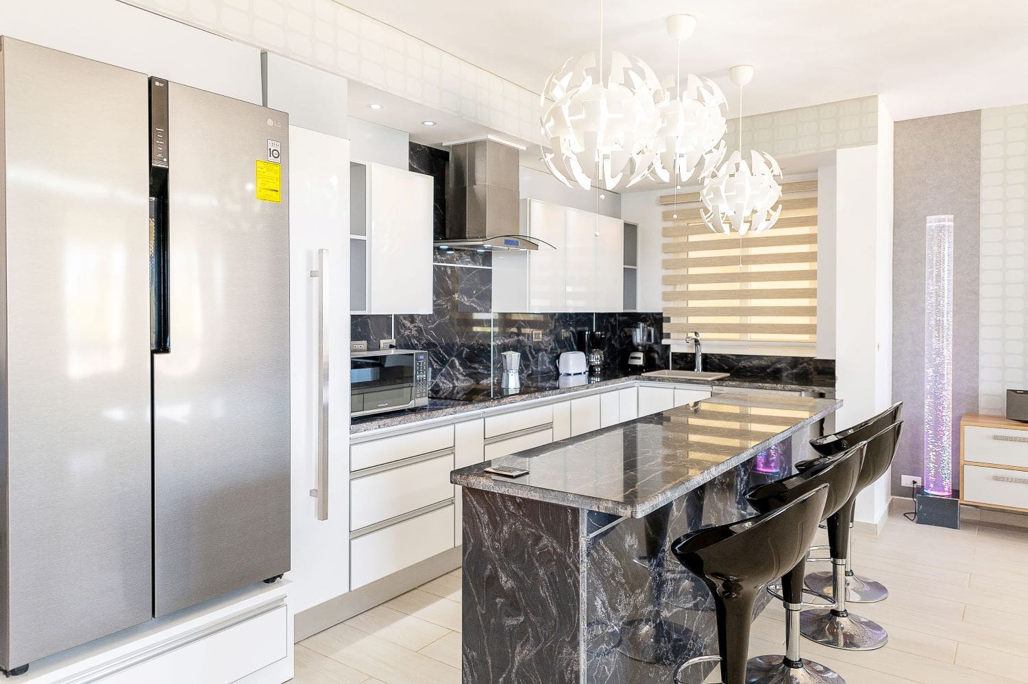 Modern white kitchen with black marble island and bar stools