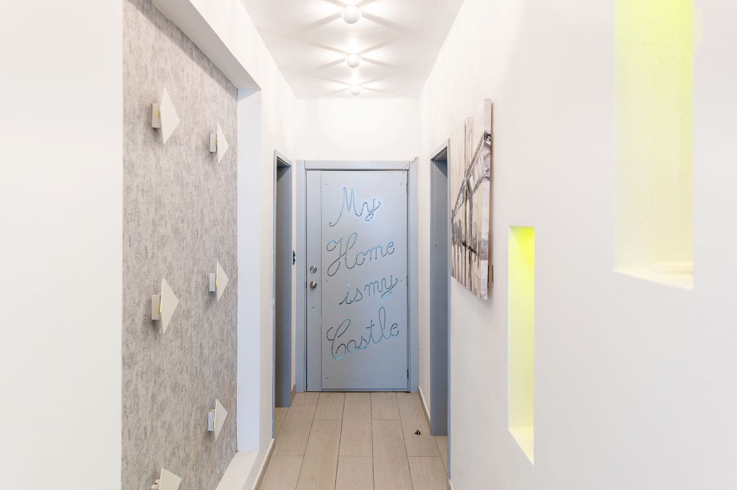 Hallway with a blue door featuring "My Home is my Castle" in cursive