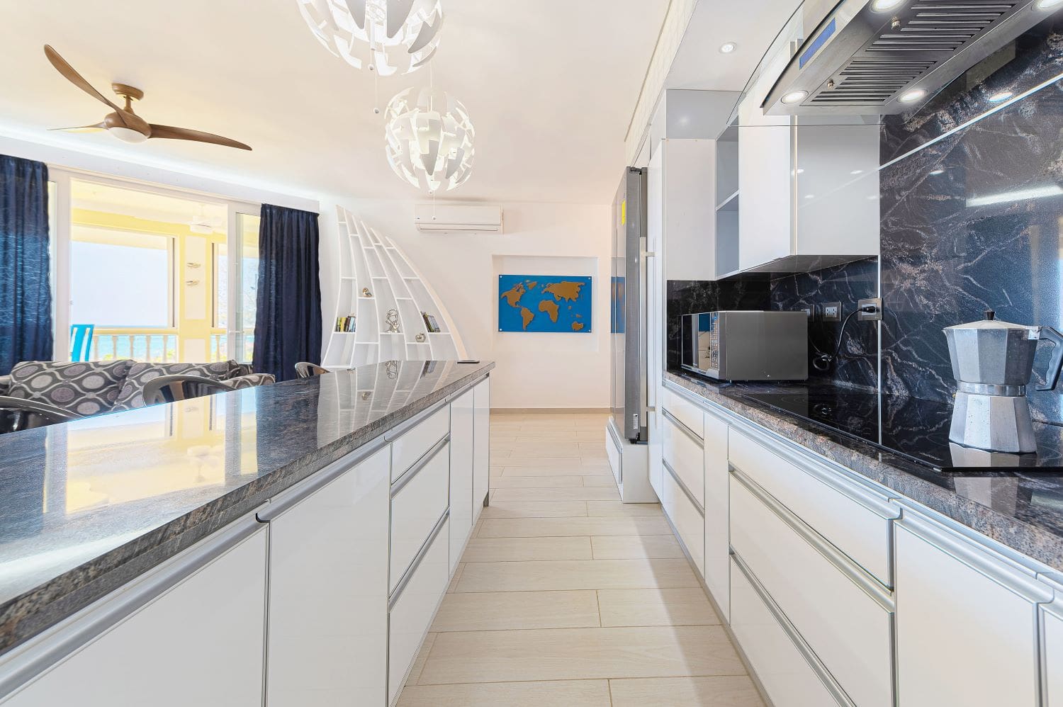 Modern open-plan kitchen with white cabinets, granite countertops, and a world map art piece.