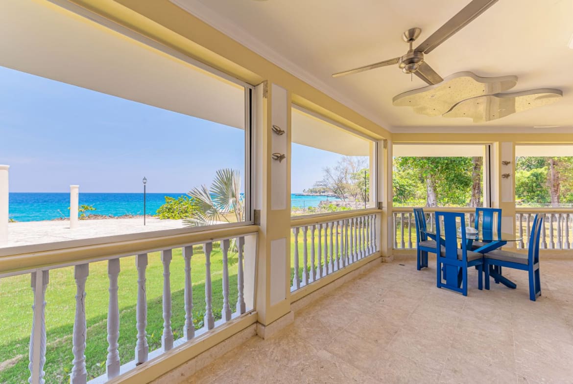 Ocean view patio with blue dining set and ceiling fan