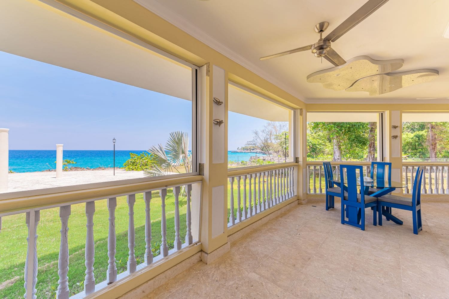 Ocean view patio with blue dining set and ceiling fan