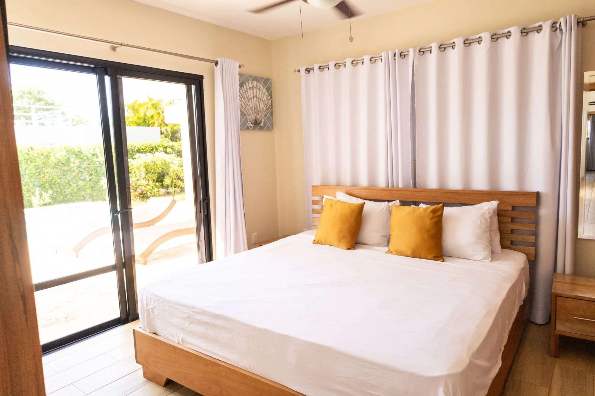 buyDRproperty Modern bedroom with king-size bed, white linens, and sliding glass doors opening to a patio. Sosua Real Estate