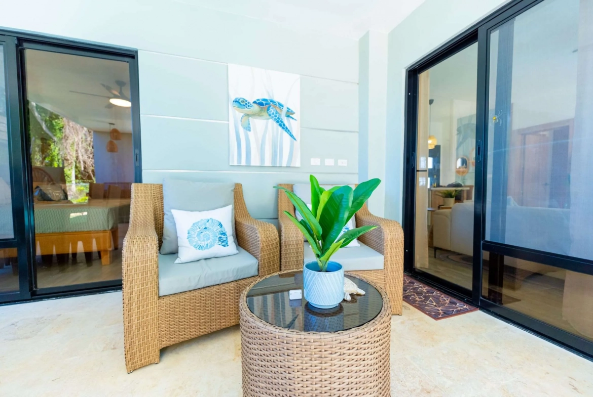 buyDRproperty Wicker chairs and table on a patio with sliding glass doors and sea turtle art. Sosua Real Estate
