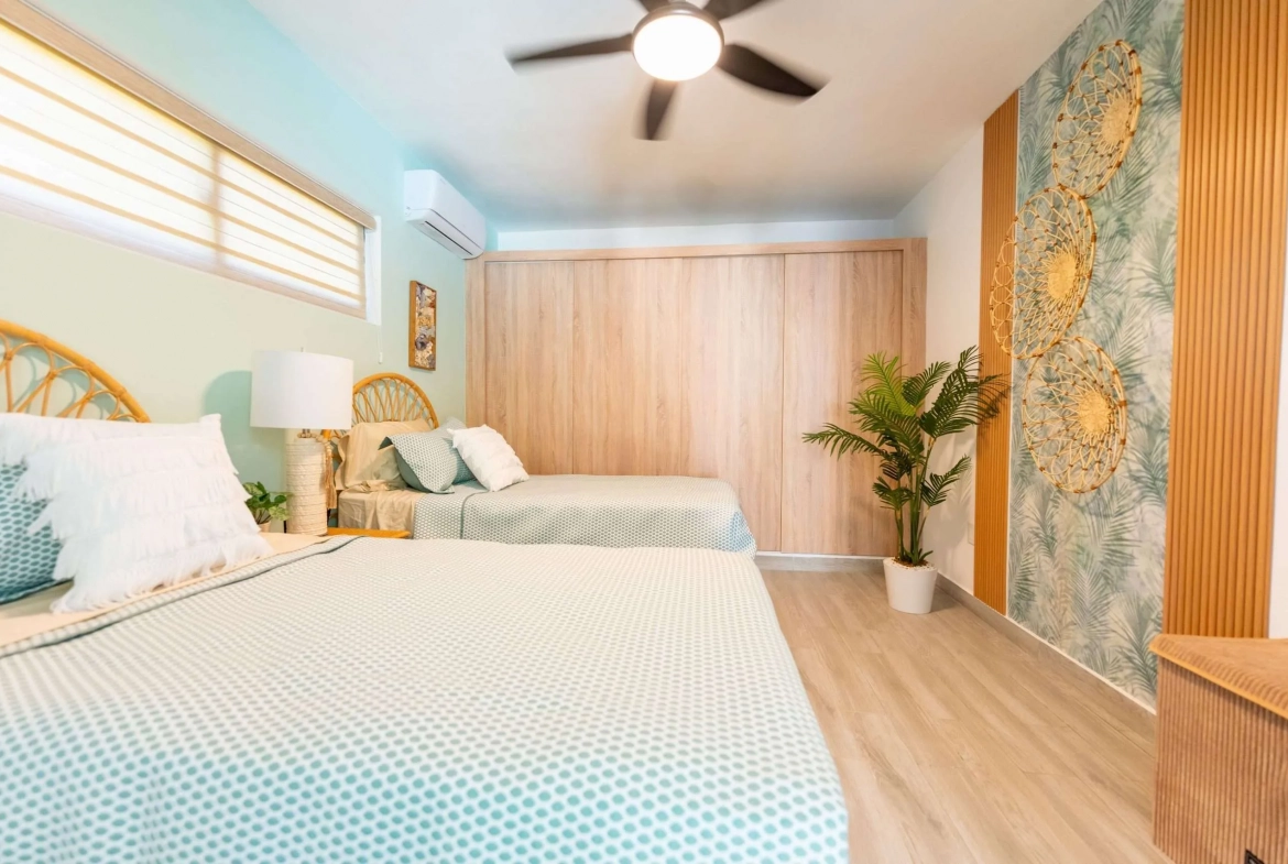 buyDRproperty Two twin beds in a tropical-themed bedroom with a large wooden closet. Sosua Real Estate