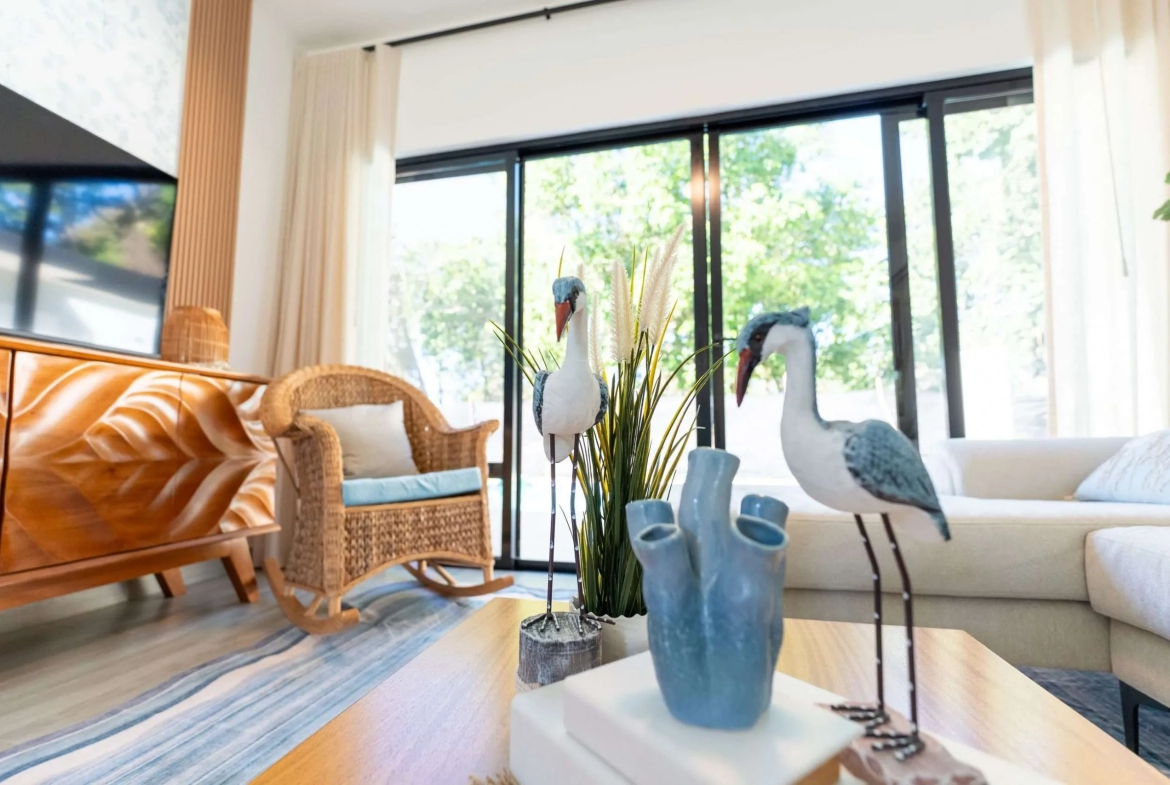 buyDRproperty Coastal living room decor with wicker chair, sofa, and bird figurines. Sosua Real Estate
