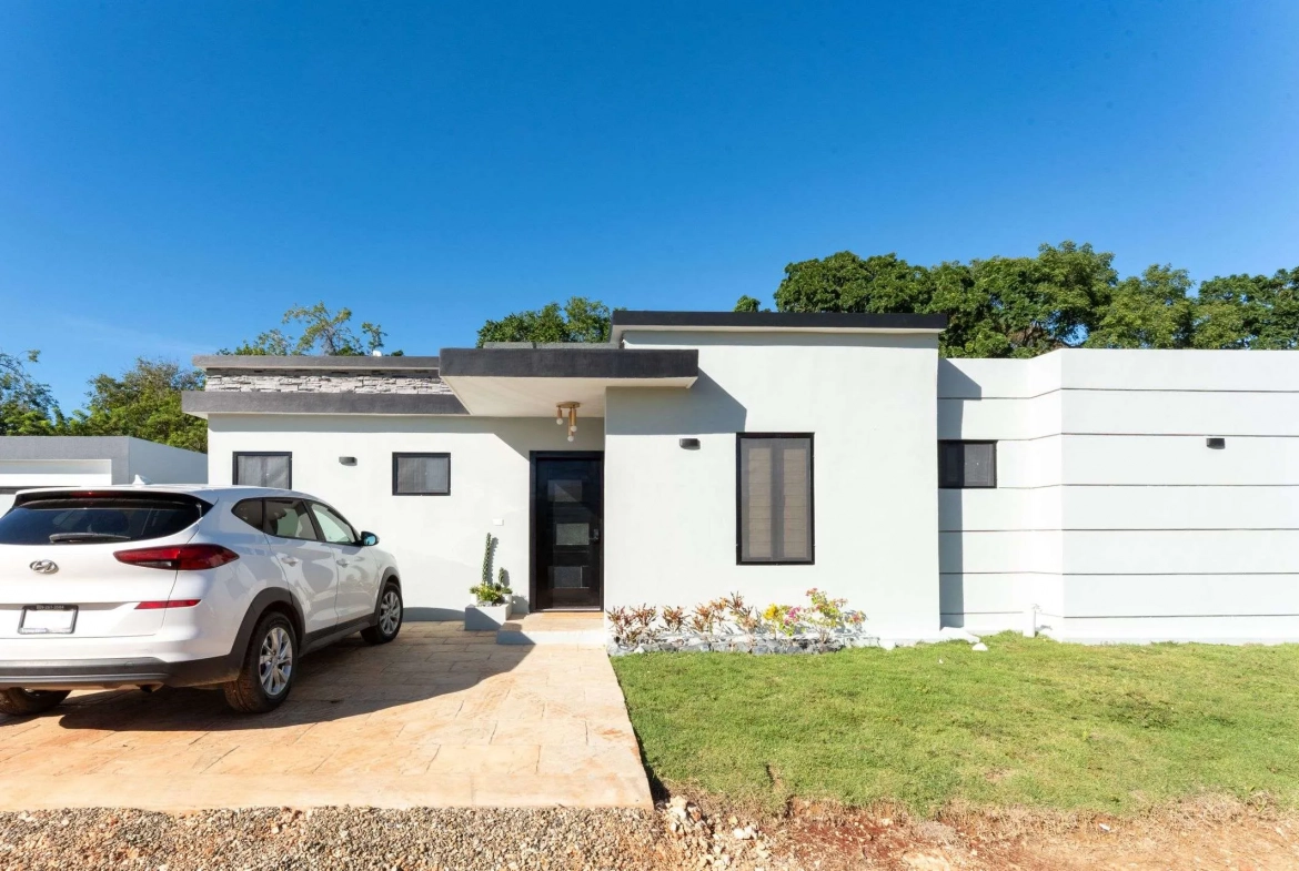 buyDRproperty Modern white house with a white SUV parked in the driveway. Sosua Real Estate