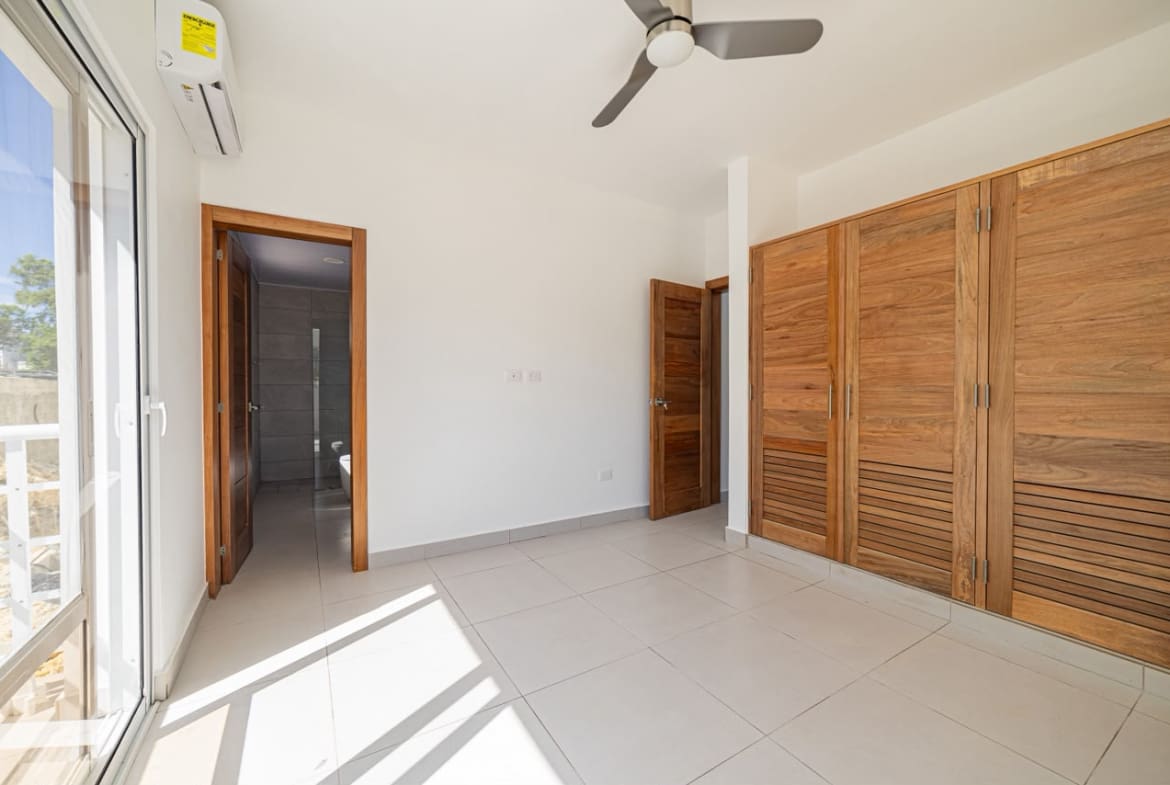 buyDRproperty Modern bedroom with wooden closet, white walls, and tiled floor Sosua Real Estate