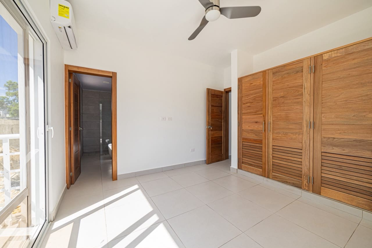 buyDRproperty Modern bedroom with wooden closet, white walls, and tiled floor Sosua Real Estate