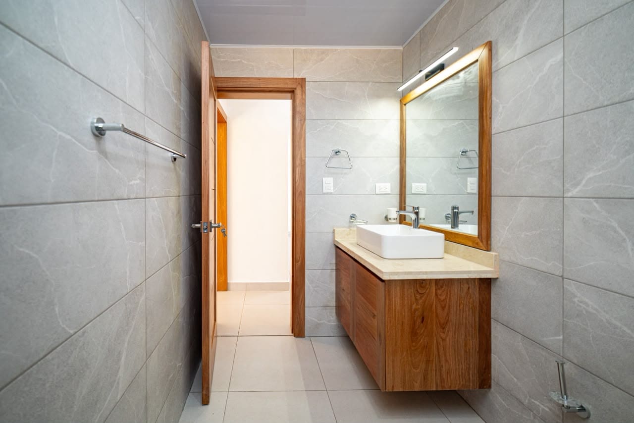 buyDRproperty Modern bathroom with a floating vanity, white vessel sink, and wood cabinets. Sosua Real Estate