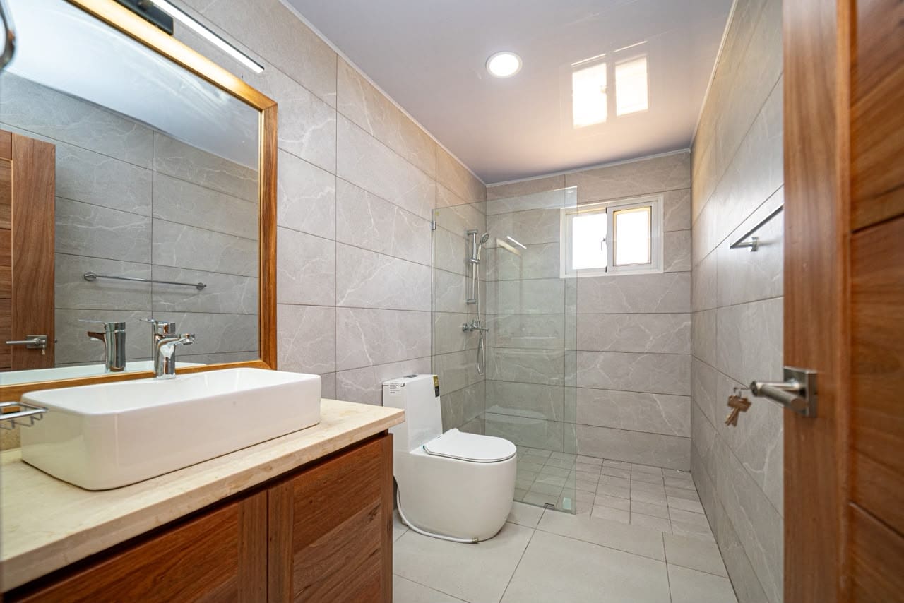 buyDRproperty Modern bathroom with vessel sink, wood vanity, and glass shower Sosua Real Estate