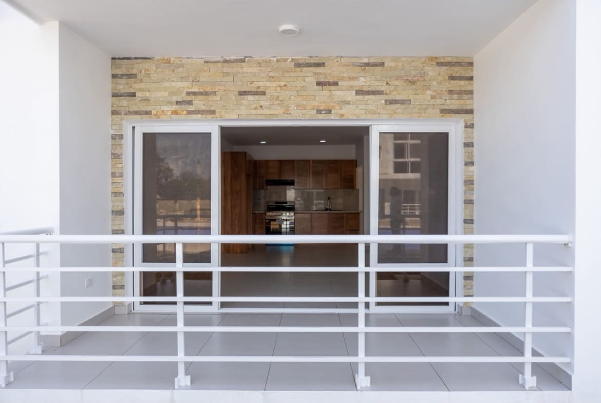 buyDRproperty Modern balcony overlooking an open-plan kitchen and living area with stone accent wall. Sosua Real Estate