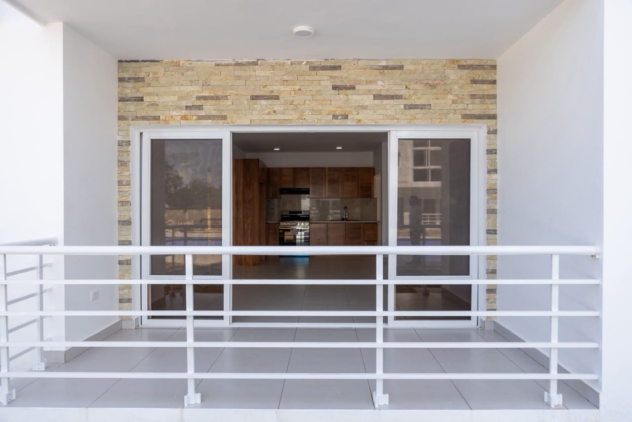 buyDRproperty Modern balcony overlooking an open-plan kitchen and living area with stone accent wall. Sosua Real Estate