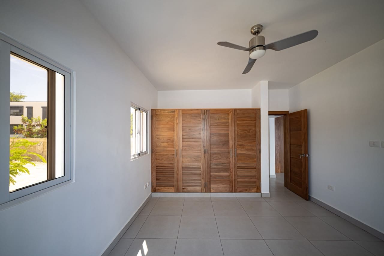 buyDRproperty Spacious bedroom with wooden louvered closet doors, ceiling fan, and window Sosua Real Estate