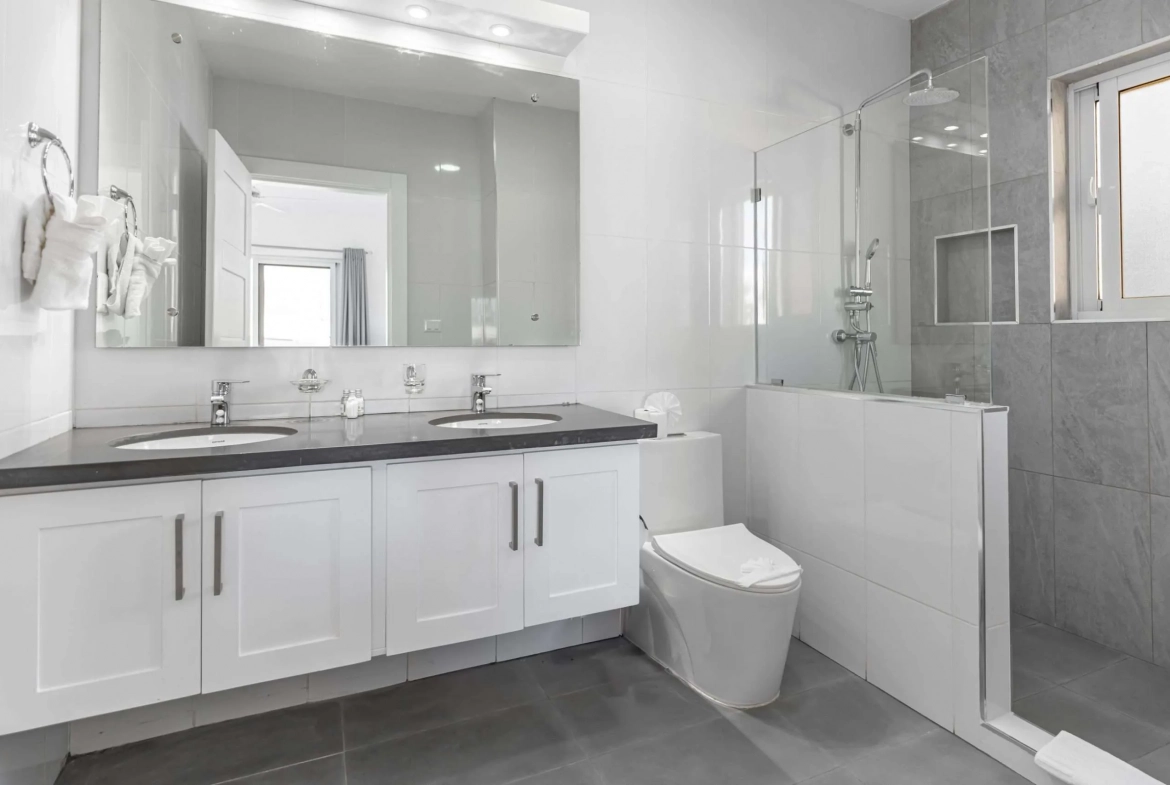 buyDRproperty Modern bathroom with double vanity, toilet, and walk-in shower Sosua Real Estate