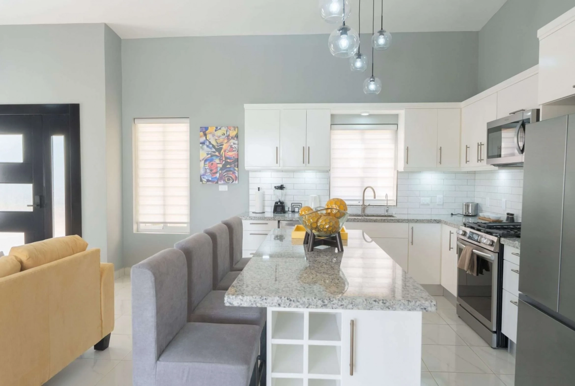 buyDRproperty Modern kitchen with island seating, white cabinets, and stainless steel appliances. Sosua Real Estate