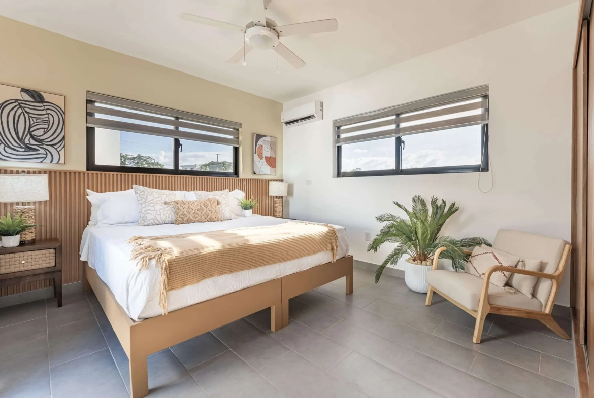 buyDRproperty Modern bedroom with king-size bed, neutral bedding, and natural light Sosua Real Estate