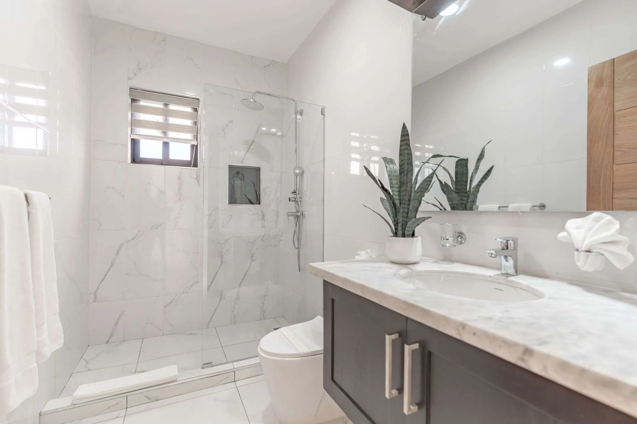 buyDRproperty Modern white marble bathroom with walk-in shower, vanity, and toilet Sosua Real Estate