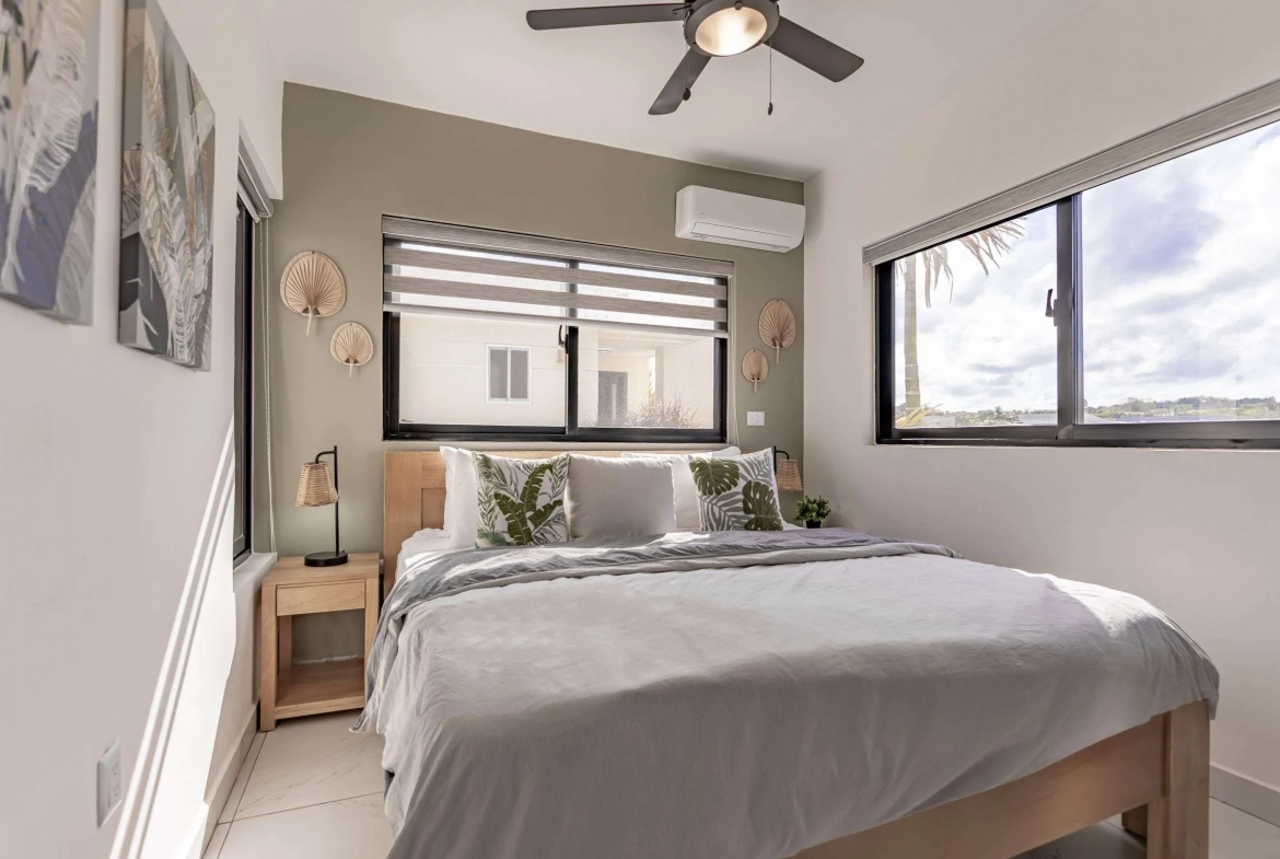 buyDRproperty Modern bedroom with king-size bed, tropical pillows, and large windows. Sosua Real Estate