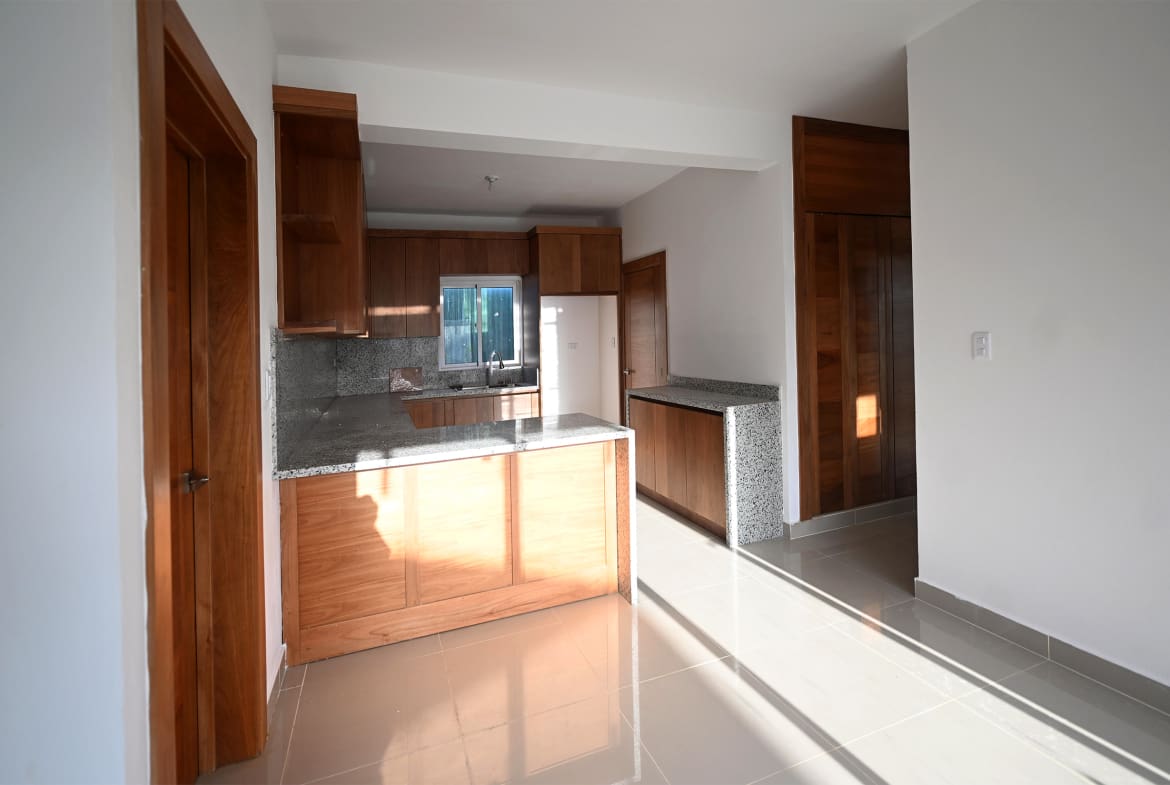 Modern kitchen with wooden cabinets, granite countertops, and tile flooring.
