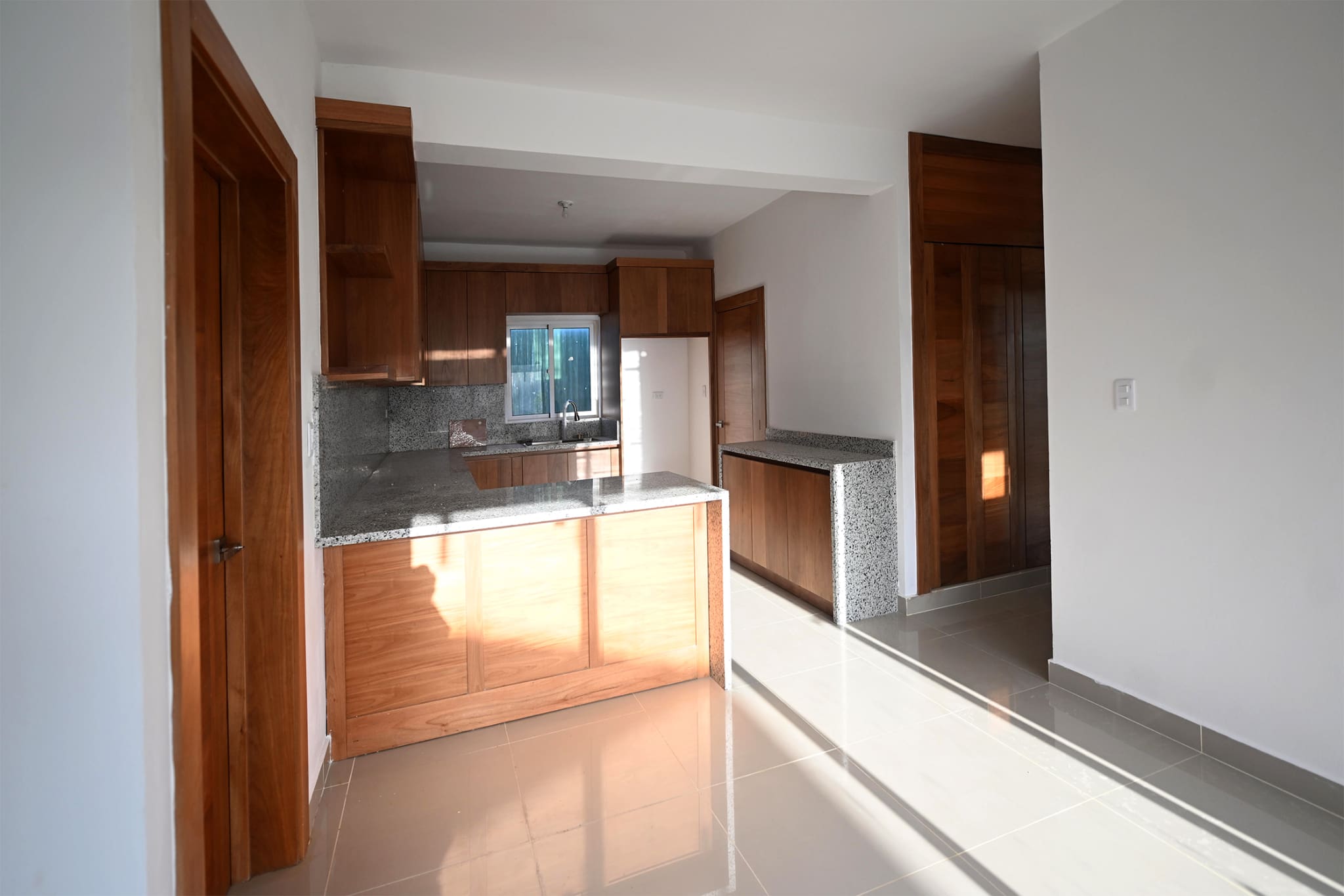 Modern kitchen with wooden cabinets, granite countertops, and tile flooring.