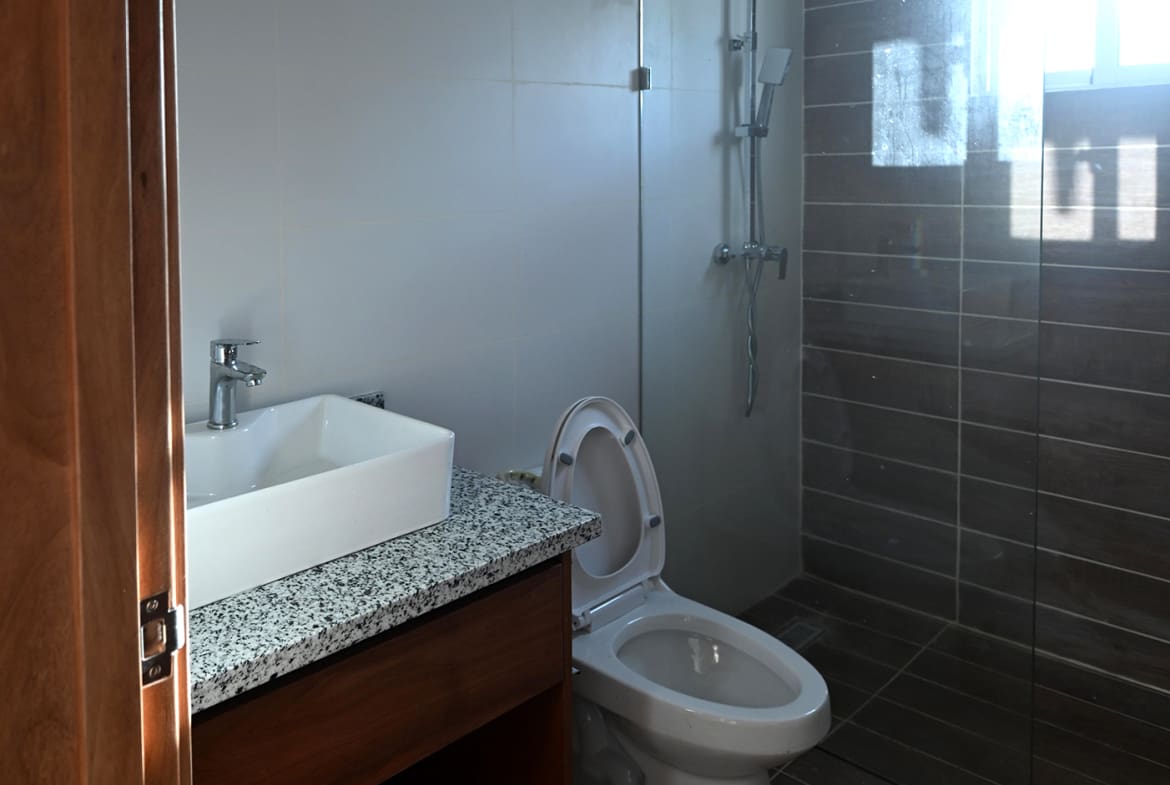 Modern bathroom with white square sink, granite countertop, and glass-enclosed shower.