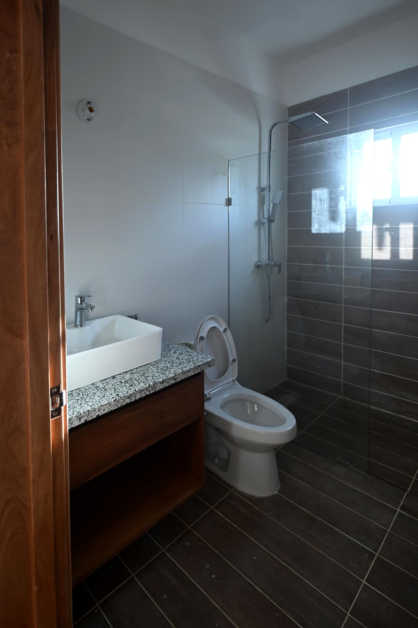 Modern bathroom with white square sink, granite countertop, and glass-enclosed shower.