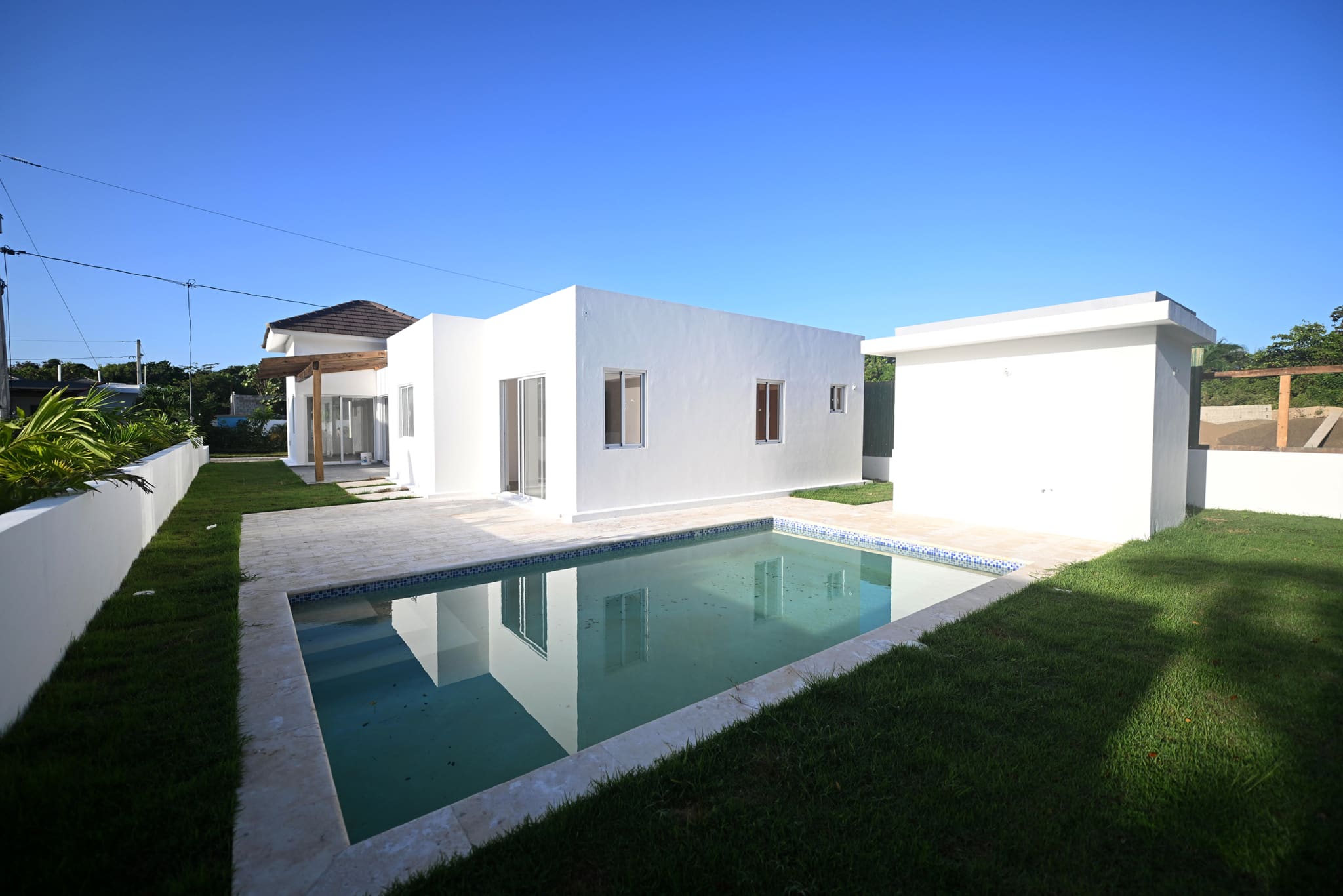Modern white house with swimming pool and green lawn, sunny day