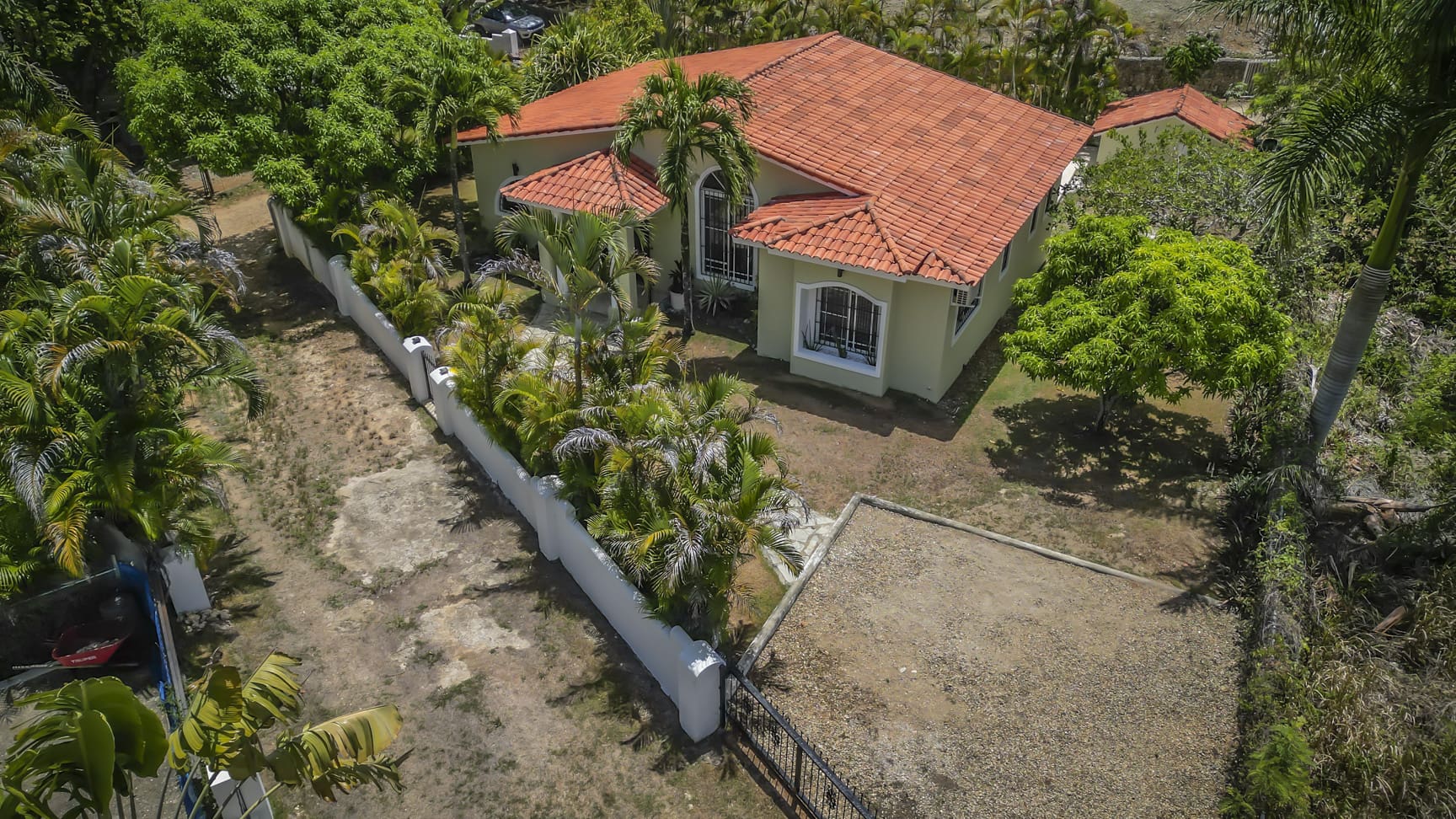 Tropical villa in La Mulata with red tile roof surrounded by lush greenery and palm trees.