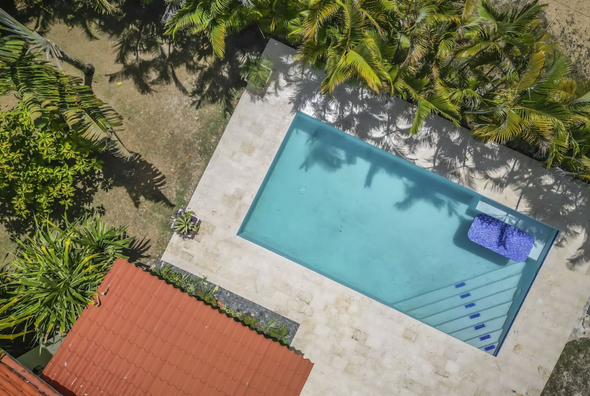 Aerial view of a tropical villa in La Mulata with a turquoise swimming pool and lush palm trees.