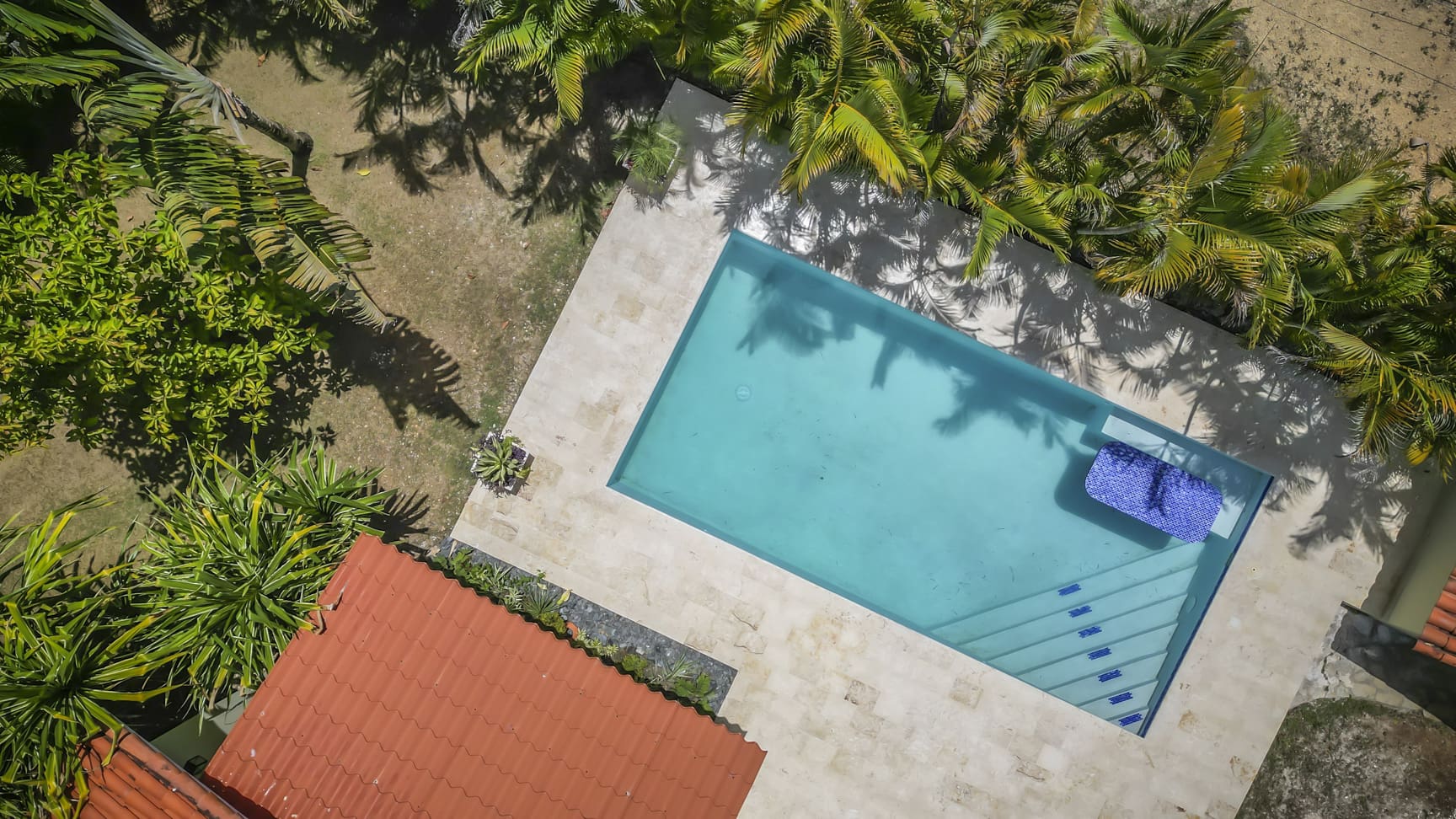 Aerial view of a tropical villa in La Mulata with a turquoise swimming pool and lush palm trees.