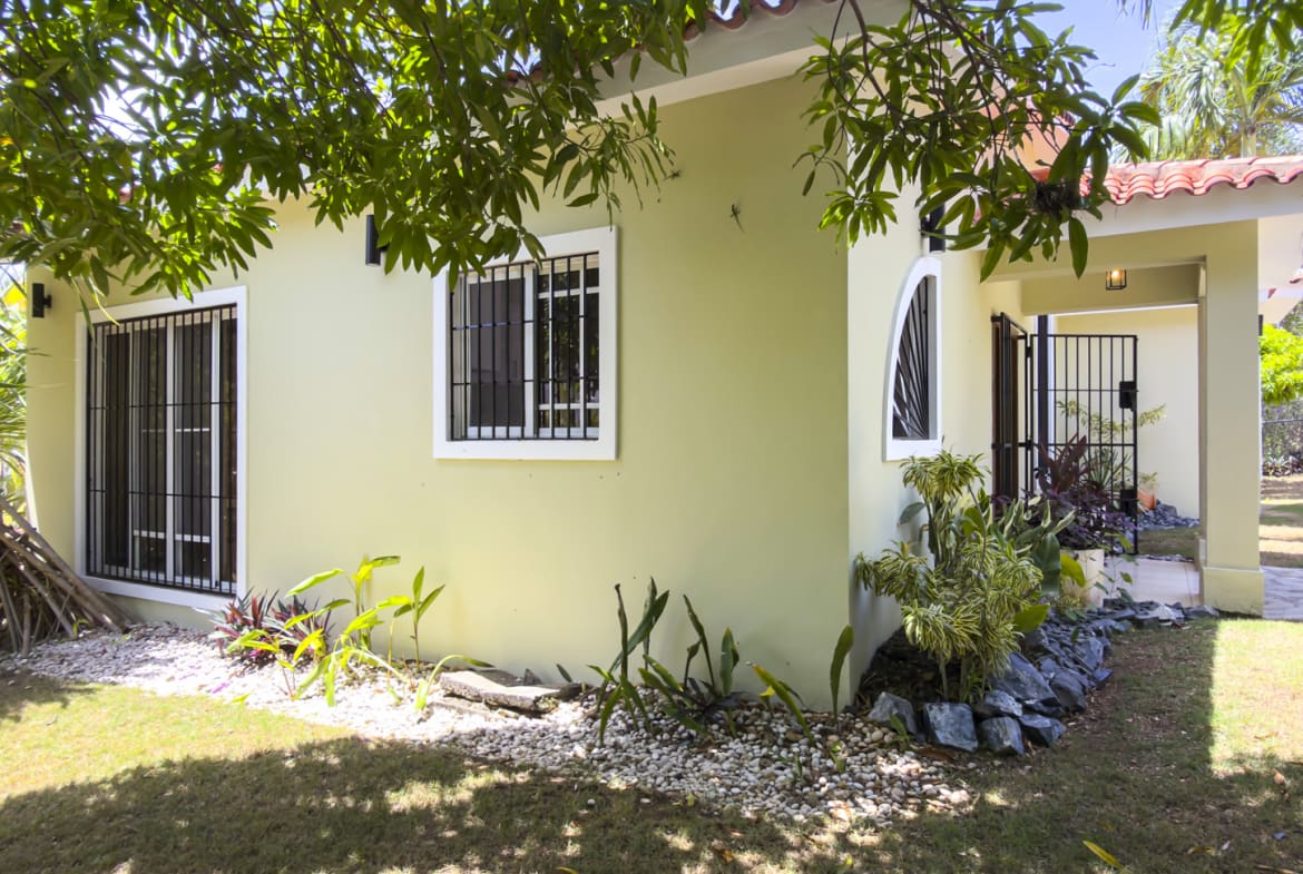 Light green Caribbean villa in Sosua with tiled roof and lush tropical landscaping.