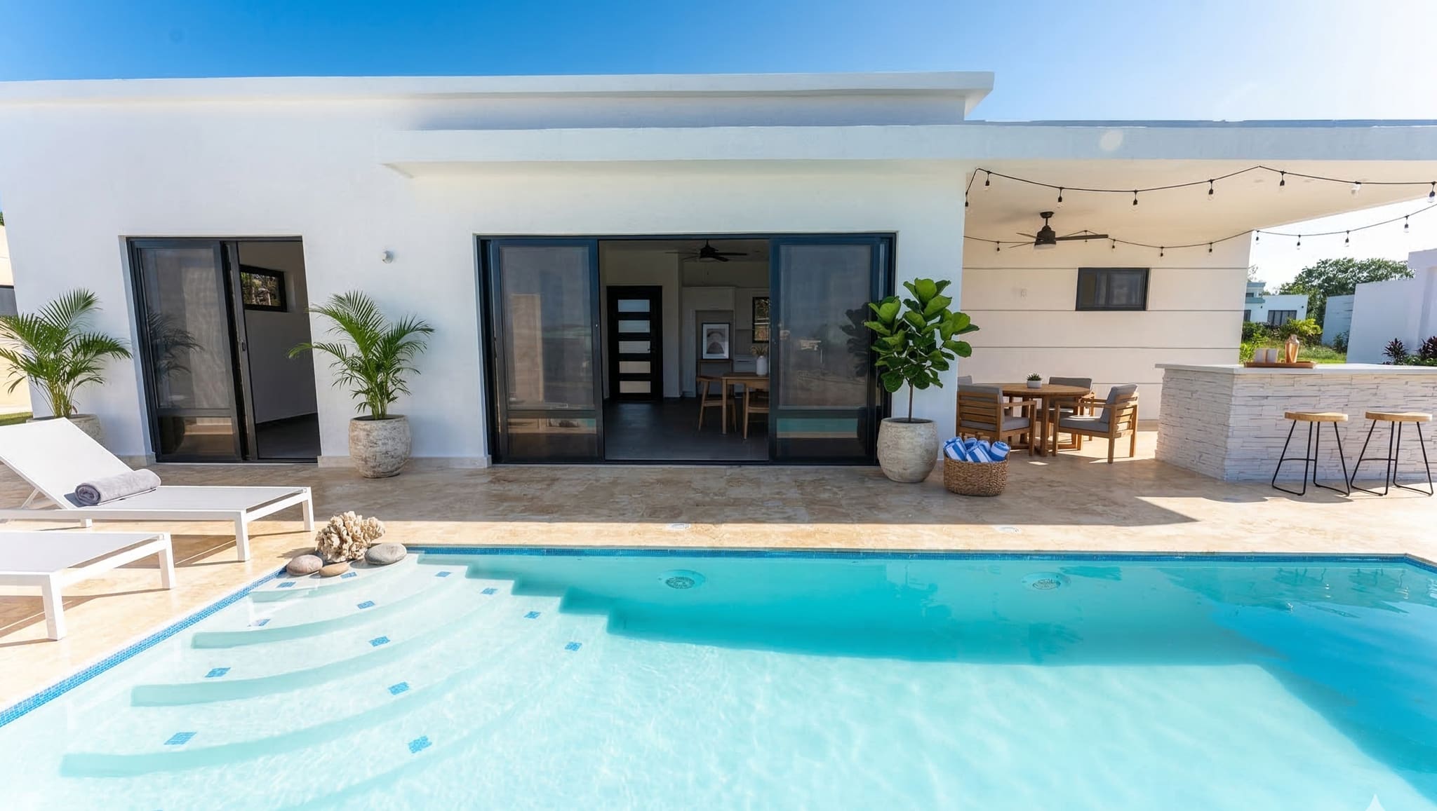 buyDRproperty Modern white villa with swimming pool, patio bar, and outdoor dining area. Sosua Real Estate