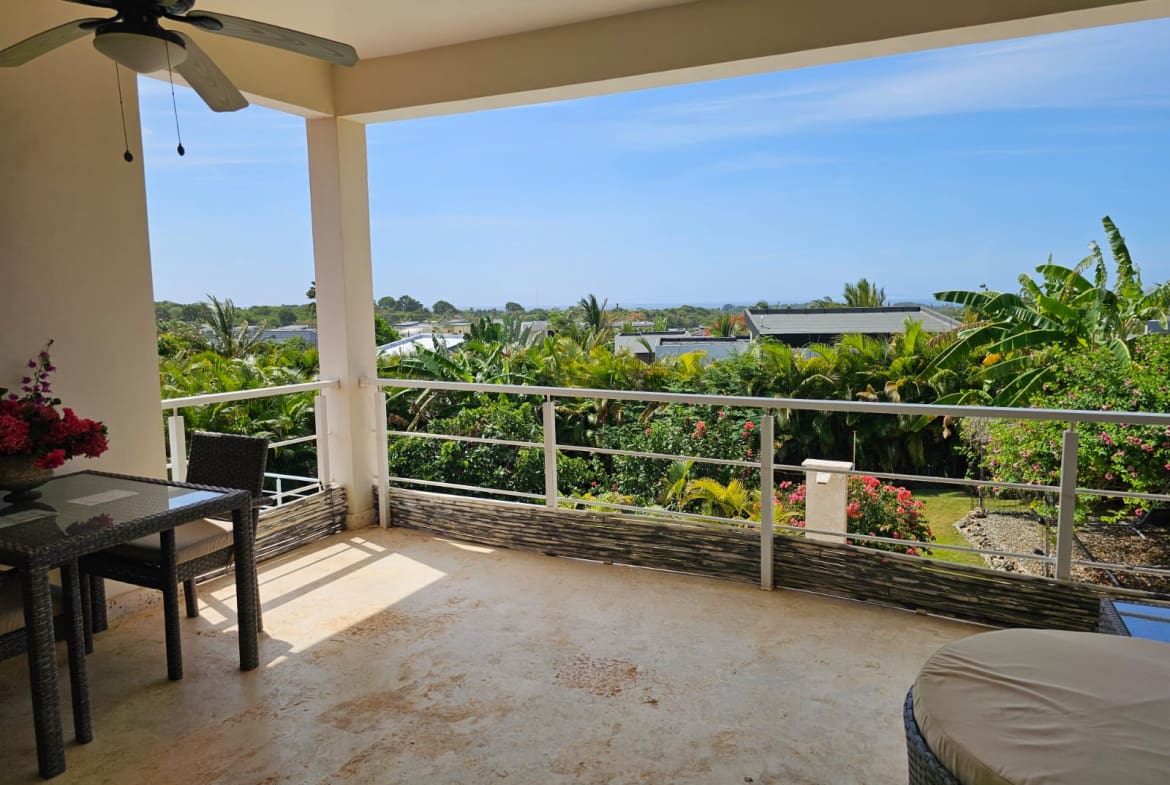 buyDRproperty Balcony view of lush tropical foliage and distant ocean from a resort. Sosua Real Estate