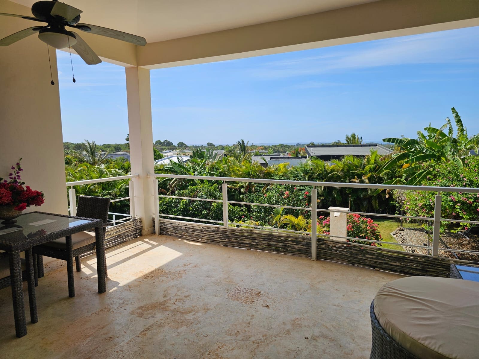 buyDRproperty Balcony view of lush tropical foliage and distant ocean from a resort. Sosua Real Estate