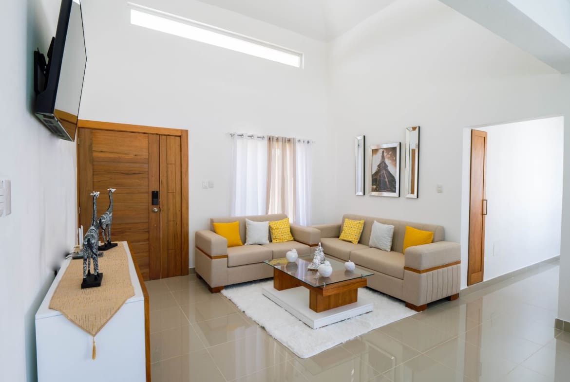 Modern living room with L-shaped sofa, glass coffee table, and neutral decor.
