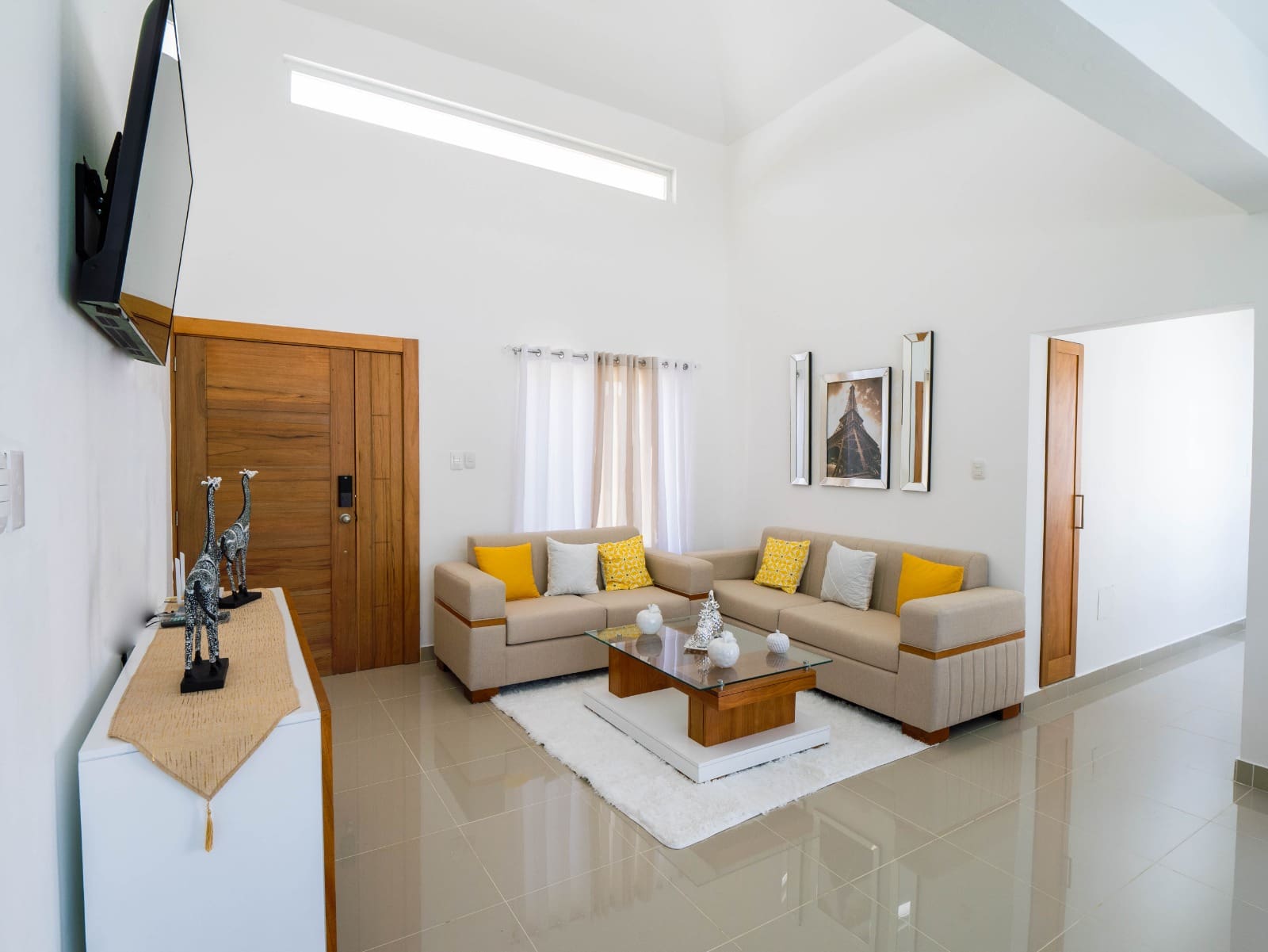 Modern living room with L-shaped sofa, glass coffee table, and neutral decor.