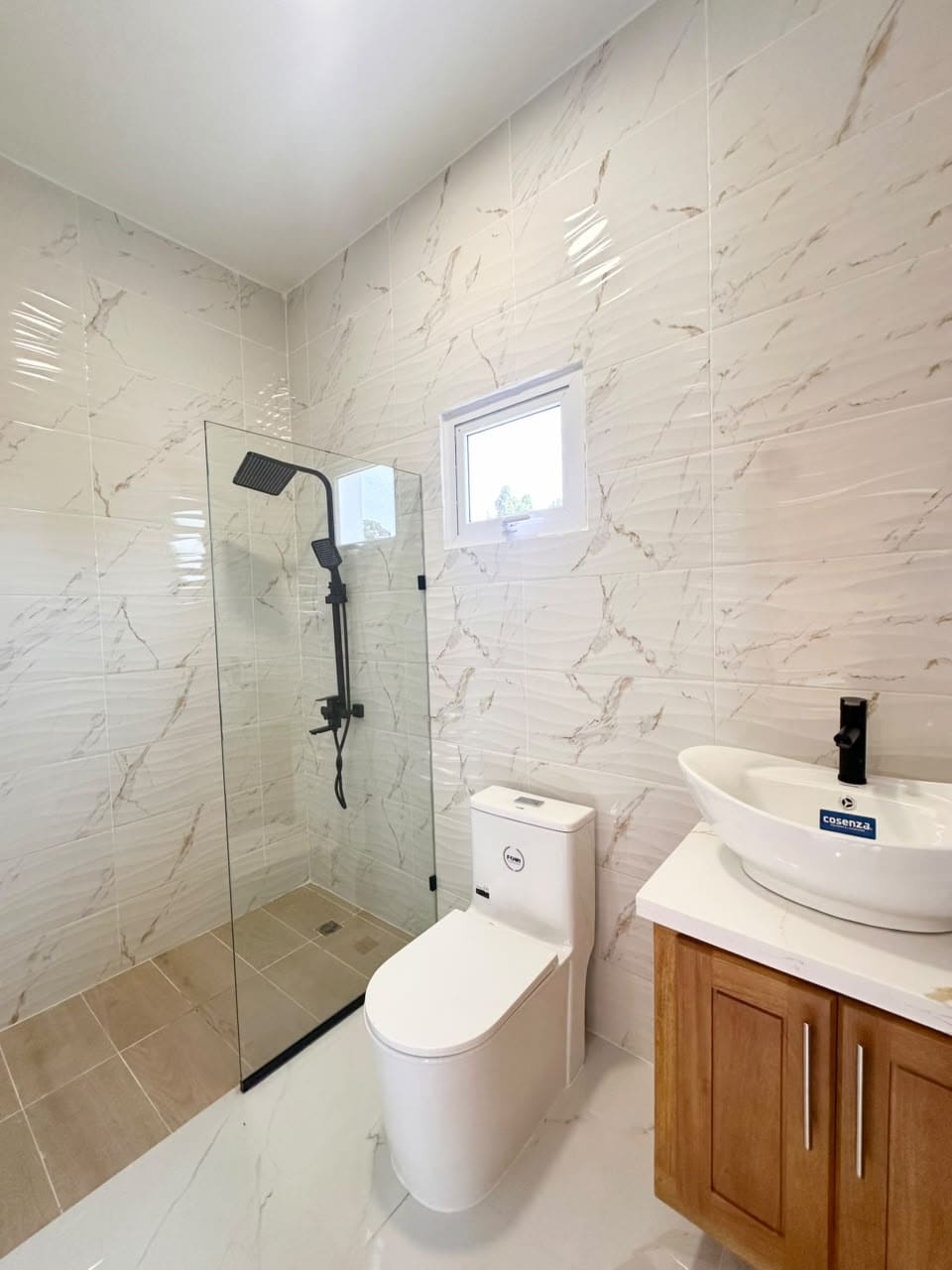 Modern bathroom with a walk-in shower, white toilet, and wooden vanity with a vessel sink.